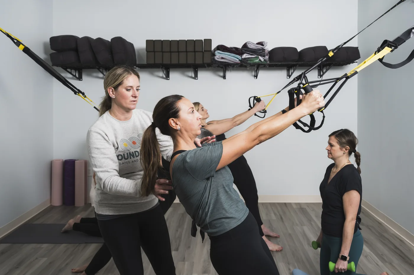Instructor giving hands-on form corrections to a client during a mat class at Foundations Pilates and Wellness Studio