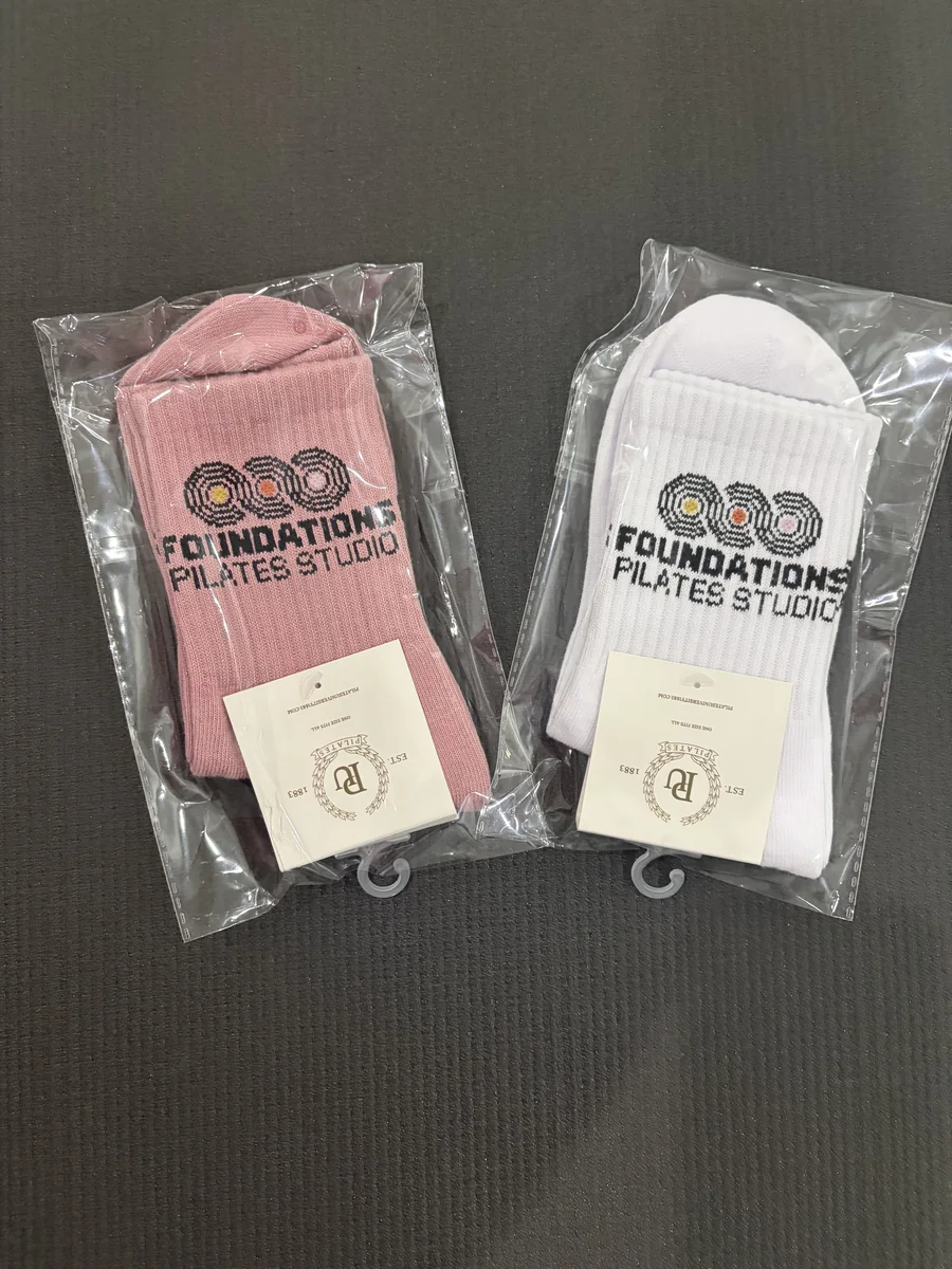 Foundations Pilates and Wellness Studio branded grip socks in pink and white