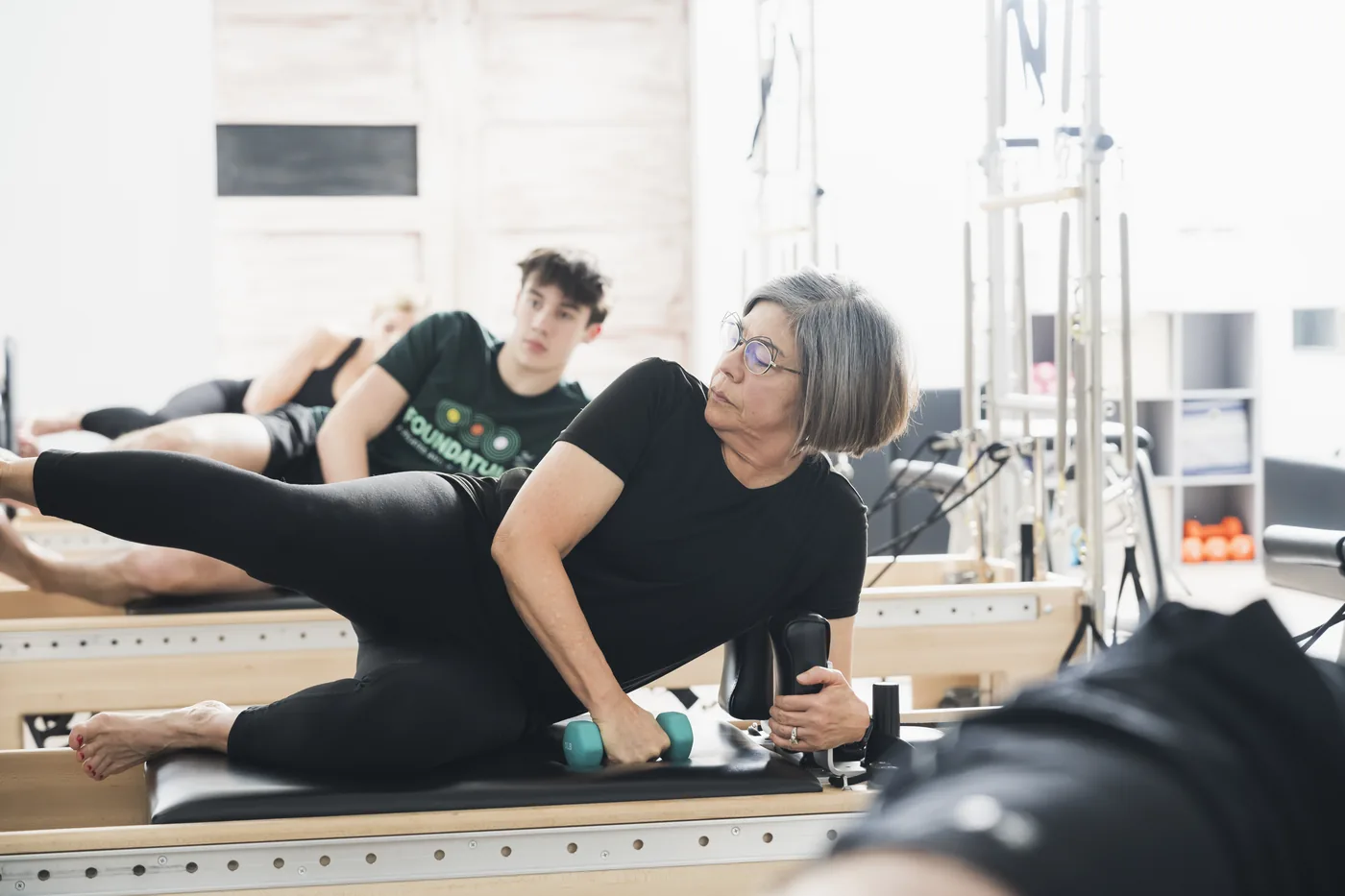 Instructor guiding a client through a slower, supported reformer stretch during Gentle Flow