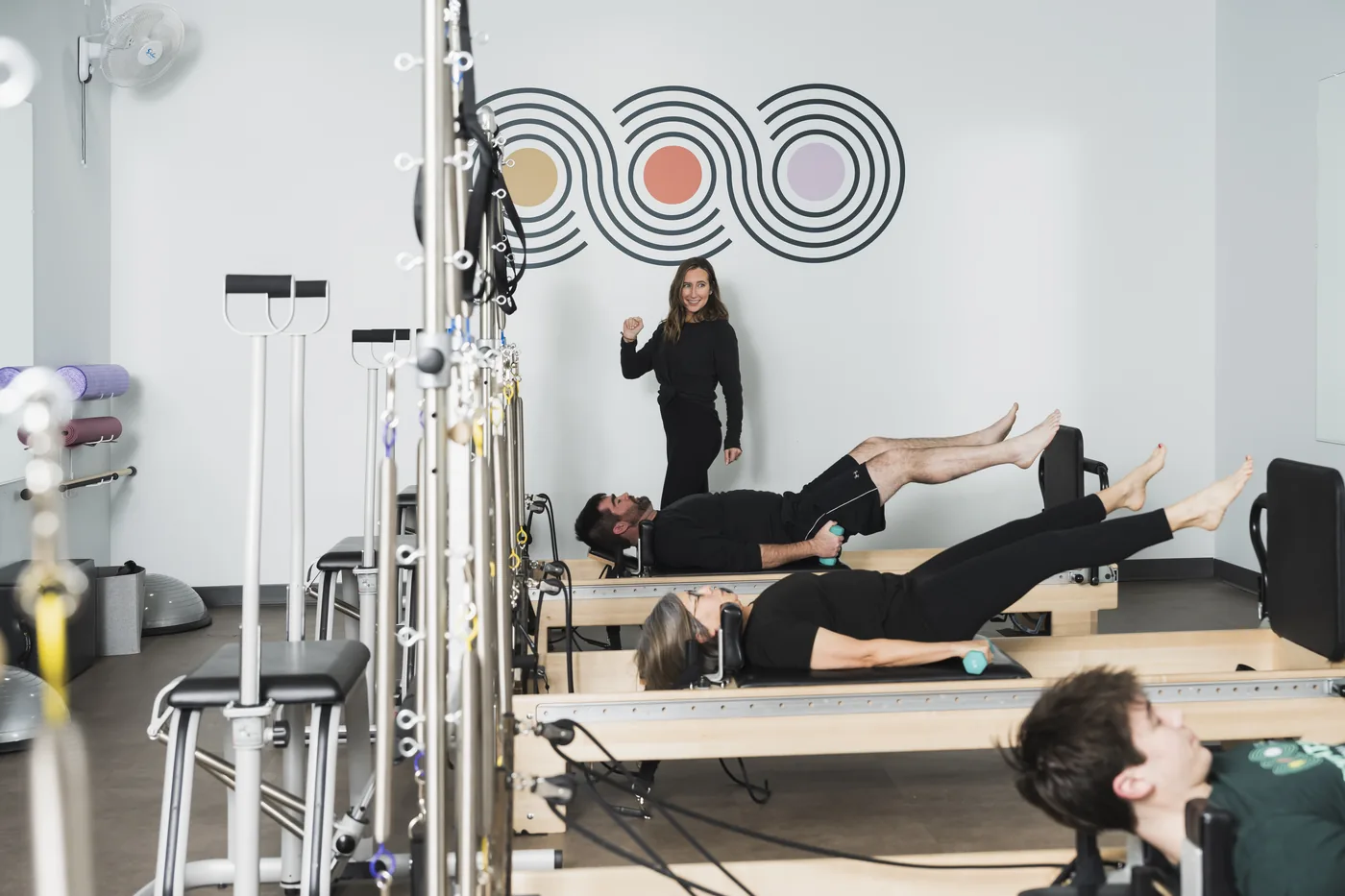Small group of clients working on reformer machines during a Group Reformer class at Foundations Pilates and Wellness Studio