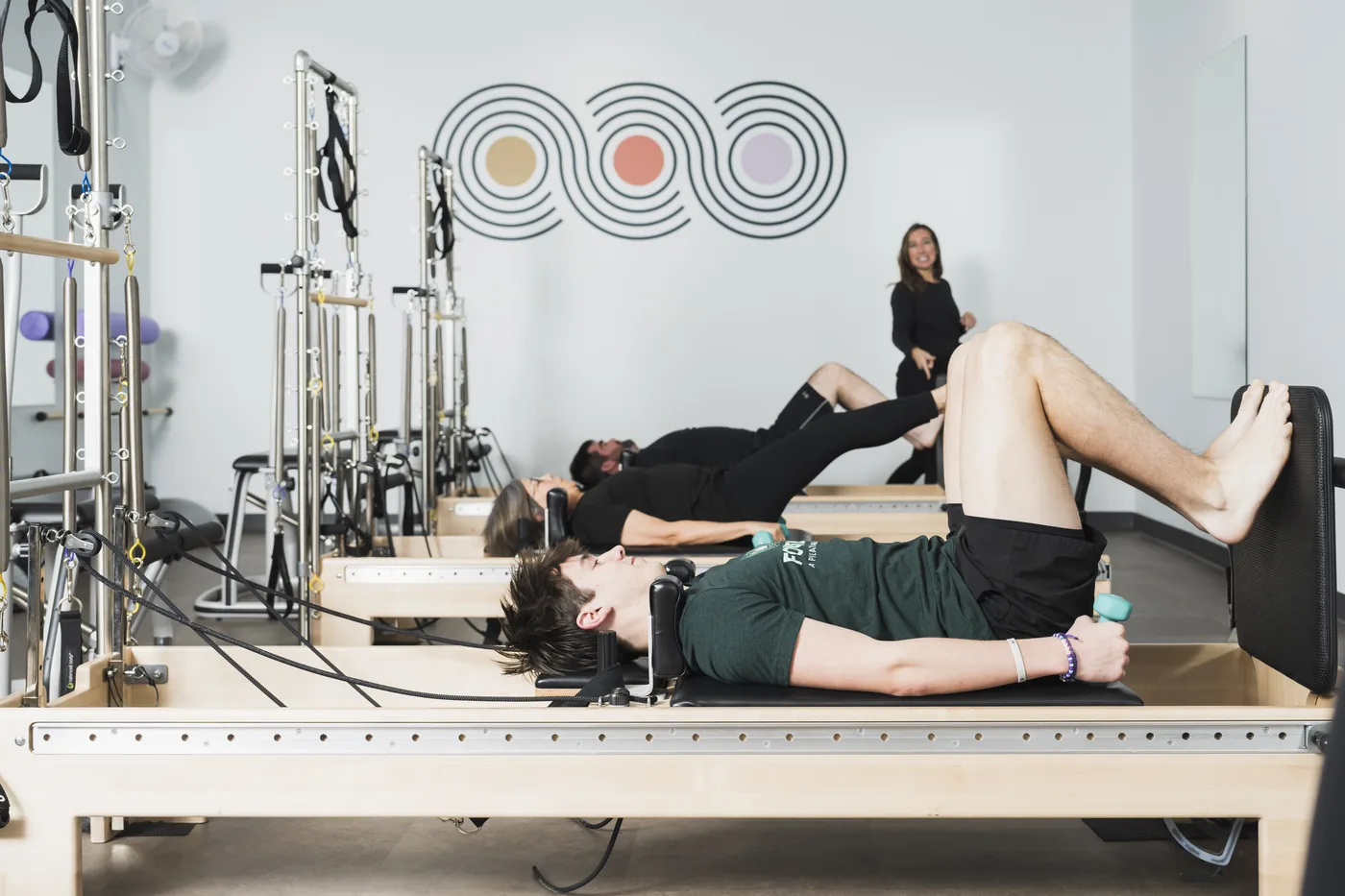 Instructor watching a new client find their footing on the reformer during Intro to Pilates Reformer